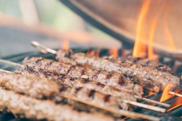 Lamb kebab skewers on a ceramic bbq at a summer garden party. Close-up.