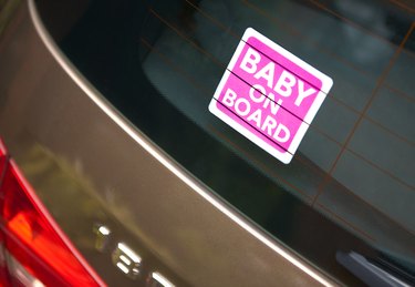 Pink Baby on Board sticker in rear view window of car