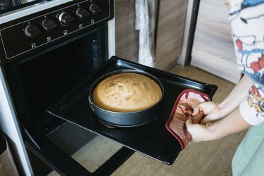 Woman removing cake from oven