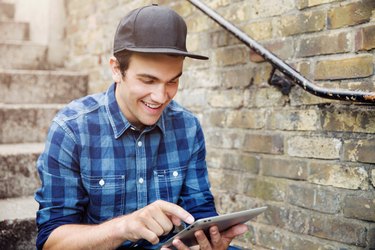 Young man sat on steps with tablet.