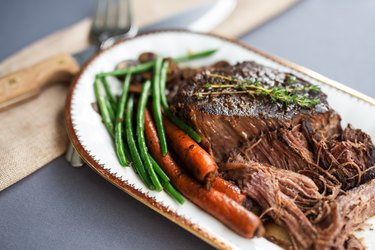 Slow cooked pot roast served with organic carrots, fresh green beans and sliced white mushrooms. Thyme garnish.