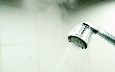 Close-Up Of Flowing Water From Shower Faucet With Steam In Bathroom