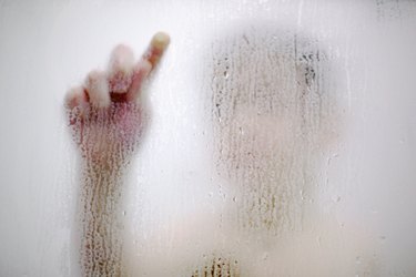 Boy drawing on glass condensation