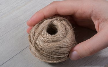 Close-Up Of Hand Holding Twine On Table