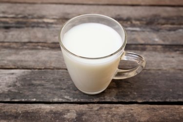 Vaso de leche de pie en la mesa de madera vieja