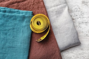 Pieces of fabric and measuring tape on wooden background