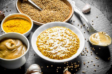 Assortment of different types of mustard on a stone Board.