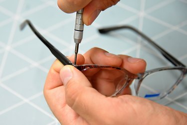 Cropped Hands Of Person Holding Tool And Eyeglasses