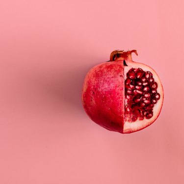 Red pomegranate fruit on pastel pink background