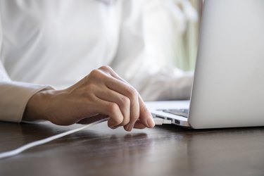 Hand of a woman plugging the cord into the USB of the personal computer