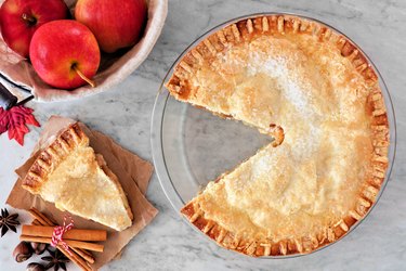 Apple pie, overhead scene with cut slice on marble background