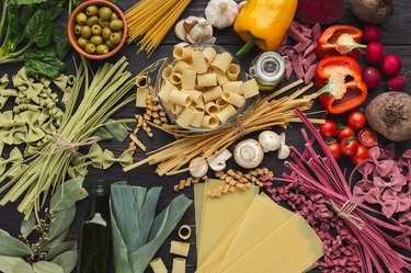 Mixed italian pasta and vegetables on brown wood, top view