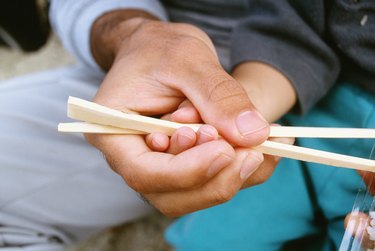 Close-up of a father teaching his son the use of chopsticks, Okinawa, Japan