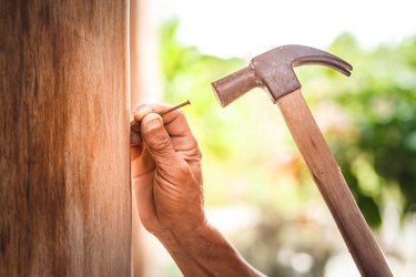 Man Hammering Nail On Wood