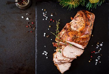 Roasted sliced ham on dark rustic background. Top view. Festival food.