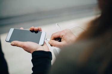 Cropped image of mature businesswoman inserting USB cable in smart phone