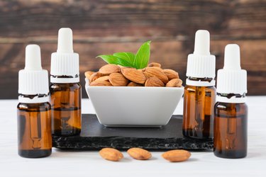 almonds in a white plate and glass bottles with oil on a black tray on a wooden table