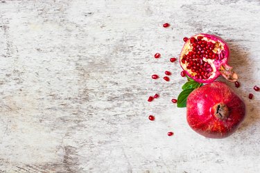 Ripe juicy pomegranate fruit on white wooden rustic background