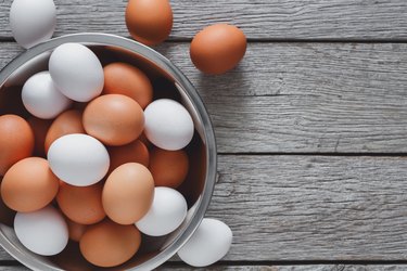 Fresh eggs in bowl on wood background