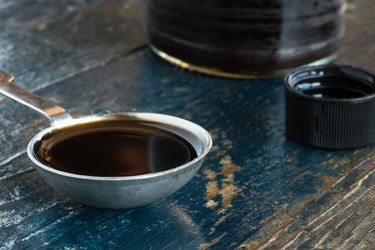 Close-Up Of Worcestershire Sauce In Tablespoon On Wooden Table