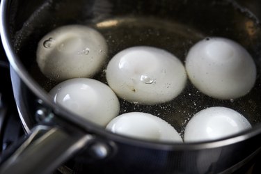 white eggs boiling in pot of hot water