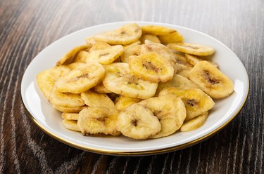 Banana chips in saucer on wooden table