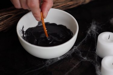 Dipping pretzel stick into black candy melts