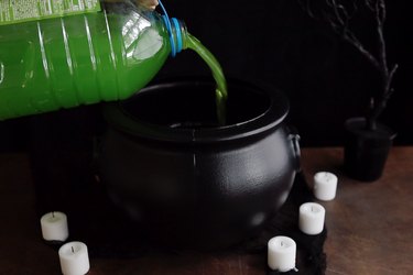 Pouring green punch into black cauldron