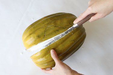 Cutting faux green pumpkin in half with knife