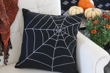 Black pillow featuring white spiderweb design