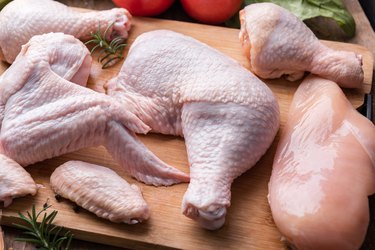 Raw chicken meat on cutting board. Legs wings and breast