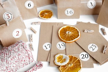 Christmas Advent calendar with paper bags, dry fruits, and string on a white table.