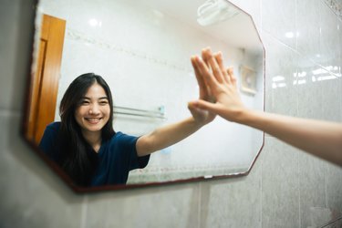Young adult smile asian woman practice self talk conversation in the morning in bathroom at home