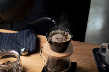 Pouring hot water over coffee grounds in a pour-over coffee maker
