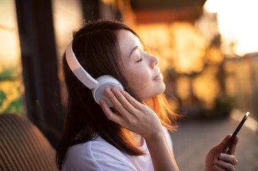 Close-up Shot Of Young Woman Enjoying Music Over Headphones And Using Smart Phone