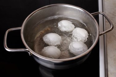 A saucepan with boiled chicken eggs on an electric stove