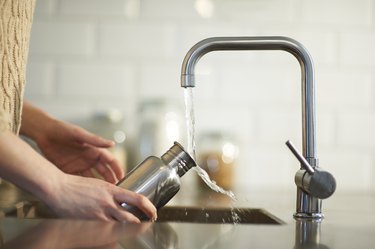 Kitchen faucet pouring water into bottle