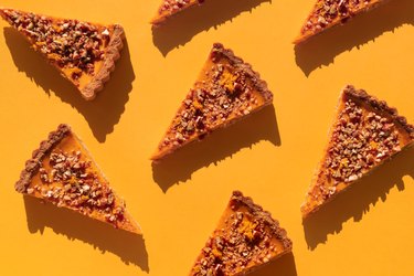 Several pieces of pumpkin cake with walnuts on orange table