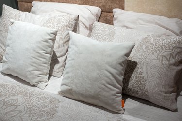 The headboard of the bed with beige colored pillows.