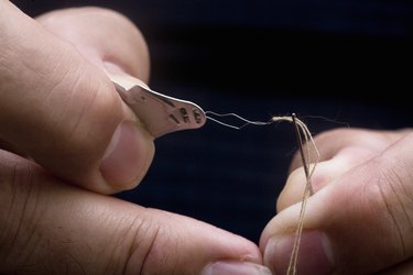 Man threading a needle with a threader