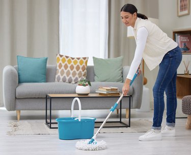 Shot of a young woman mopping her living room floors