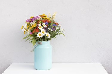 Bouquet of bright flowers in tin can vase on white table. Template for postcard. Concept Women's day, Mothers Day, Hello summer or Hello spring Copy space Front view