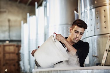 Male worker adding dry ice in wine
