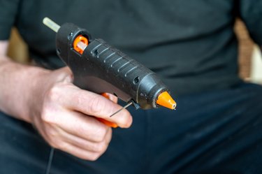 Close-up of a man holding a glue gun. A grown man with a hand tool.