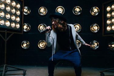 men singer with long hair, with microphone on the stage