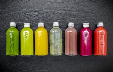 Colorful healthy smoothies and juices in bottles on dark stone background