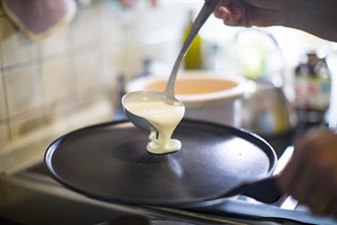 Pouring pancake batter onto a griddle pan with a ladle