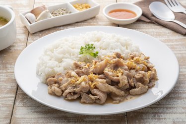 Stir-Fried Pork with Garlic and and pepper with cooked thai jasmine rice in white plate