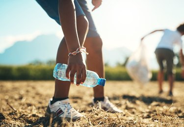 Shot of an unrecognisable teenager picking up litter off a field at summer camp