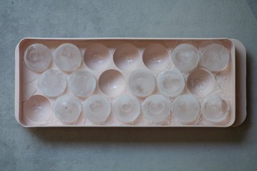 A frozen round ice in the plastic tray. The concept of making ice in home